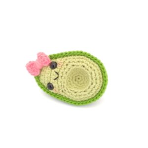amigurumi de aguacate niña con moño rosa acostado de lado