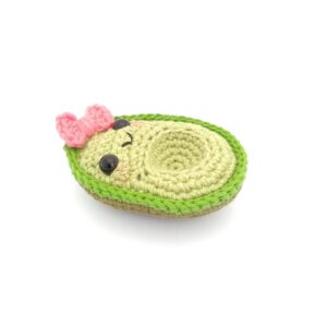 amigurumi de aguacate niña con moño rosa acostado